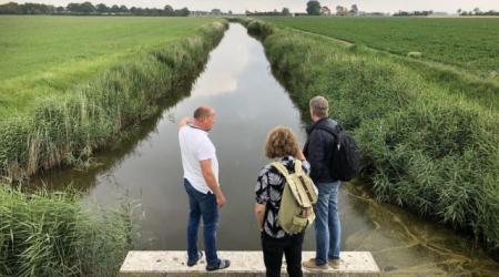 Drie mensen bij een watergang